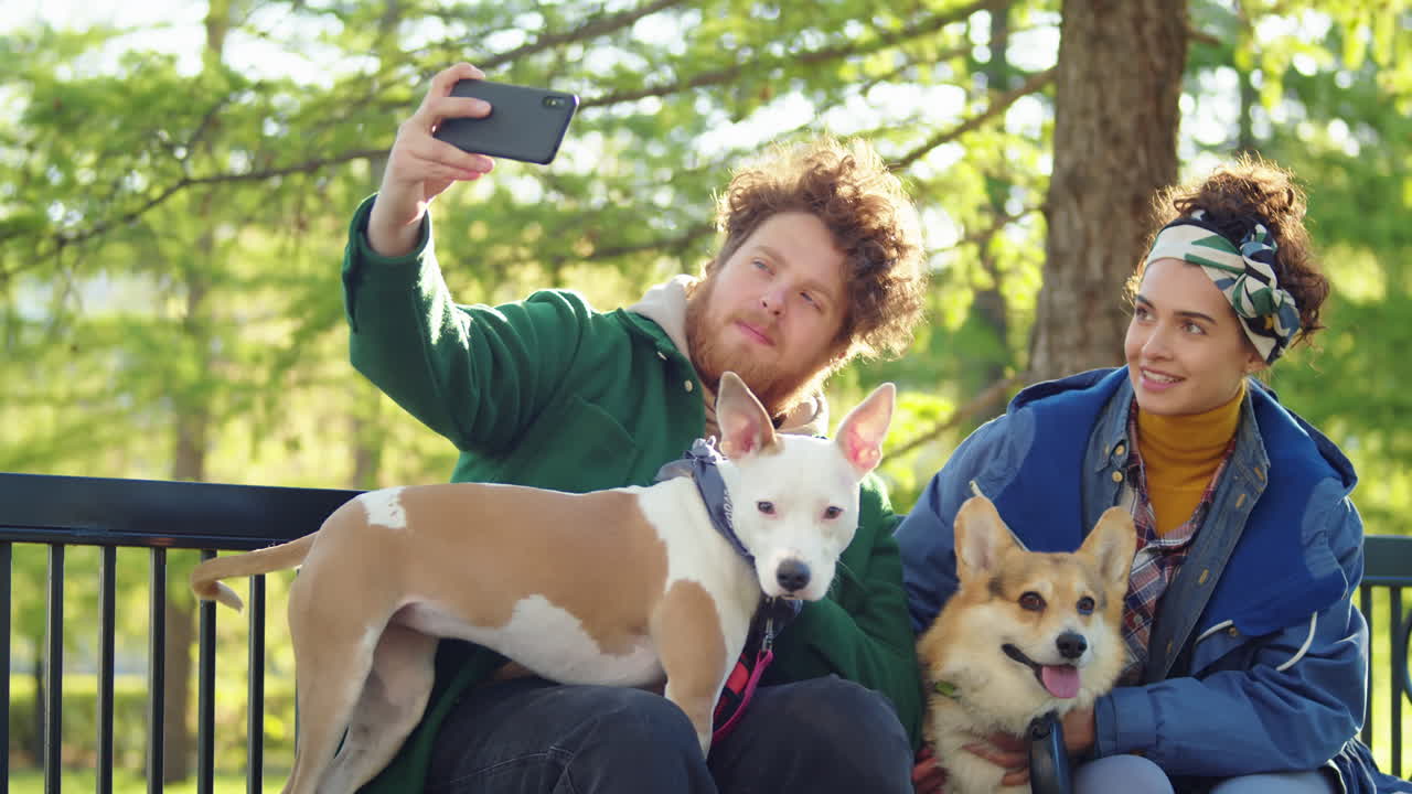 Couple and their dogs taking a selfie on a park bench