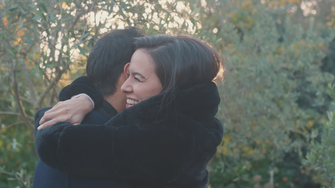 사랑하는 젊은 커플이 뜨거운 빛에 맞서 가을이나 겨울 시골에서 야외에서 만나고 포옹합니다.