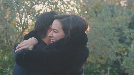 una pareja de jóvenes enamorados se reúnen y se abrazan al aire libre en el campo de otoño o invierno contra el sol abrasador