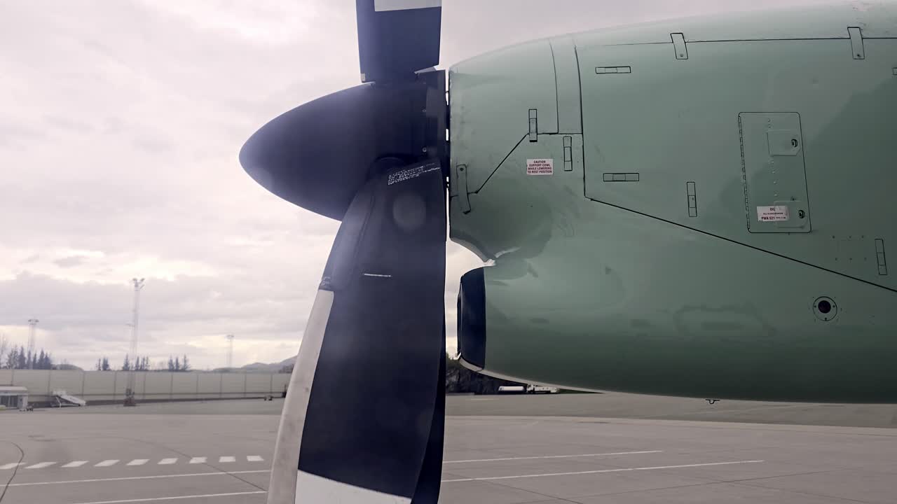 Looking out window of parked twin propeller aircraft at Norwegian airport as propeller slows down
