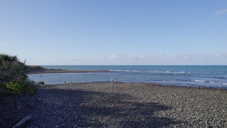 Revelador-Disparo-De-Dos-Personas-Arrojando-Piedras-Al-Mar-En-La-Desembocadura-Del-Arroyo-Emmagen-En-Cape-Tribulation,-Queensland