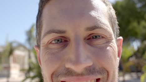 Portrait-of-happy-caucasian-man-looking-at-camera-at-beach-house