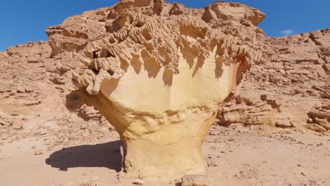 mushroom shaped rock standing beside red sandstone rockface in desert, egypt