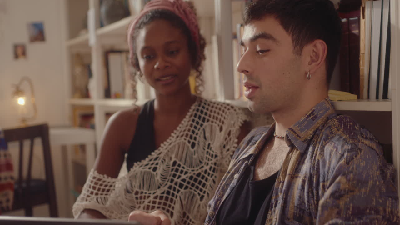 Gen Z Couple Talking and Browsing the Web on Laptop at Home