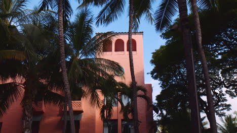 torre de hotel rosa con palmeras de coco esbeltas en un día soleado en waikiki, oahu