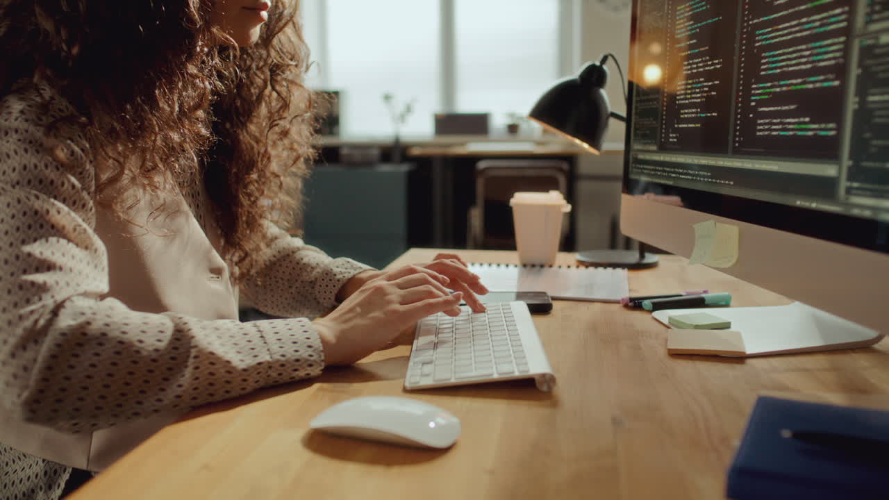Female Developer Typing Code on Computer at Desk in Office