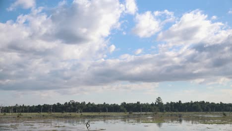 Wide,-exterior,-Time-lapse-Shot-of-White-Clouds-Drifting-Above-Flood-Plain-in-Daytime