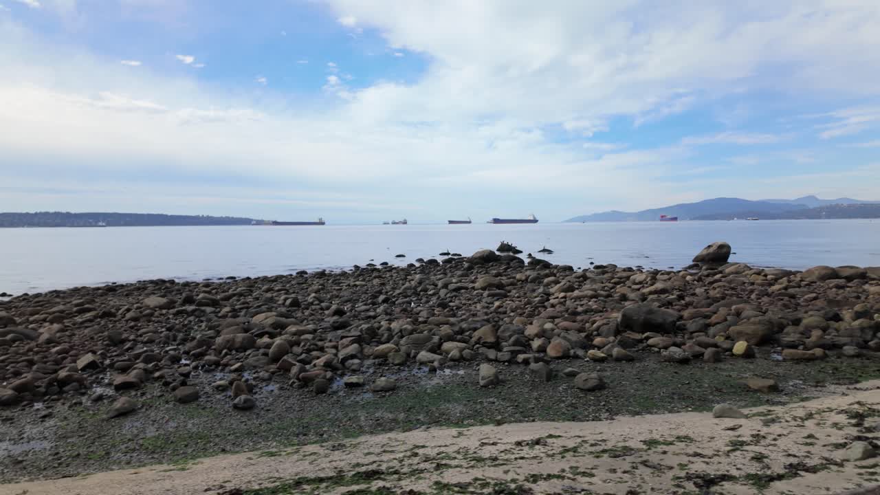 Gimbal wide dolly shot of the rocky shore along the seawall at English Bay in Vancouver, British Columbia, Canada. 4K at 30 FPS