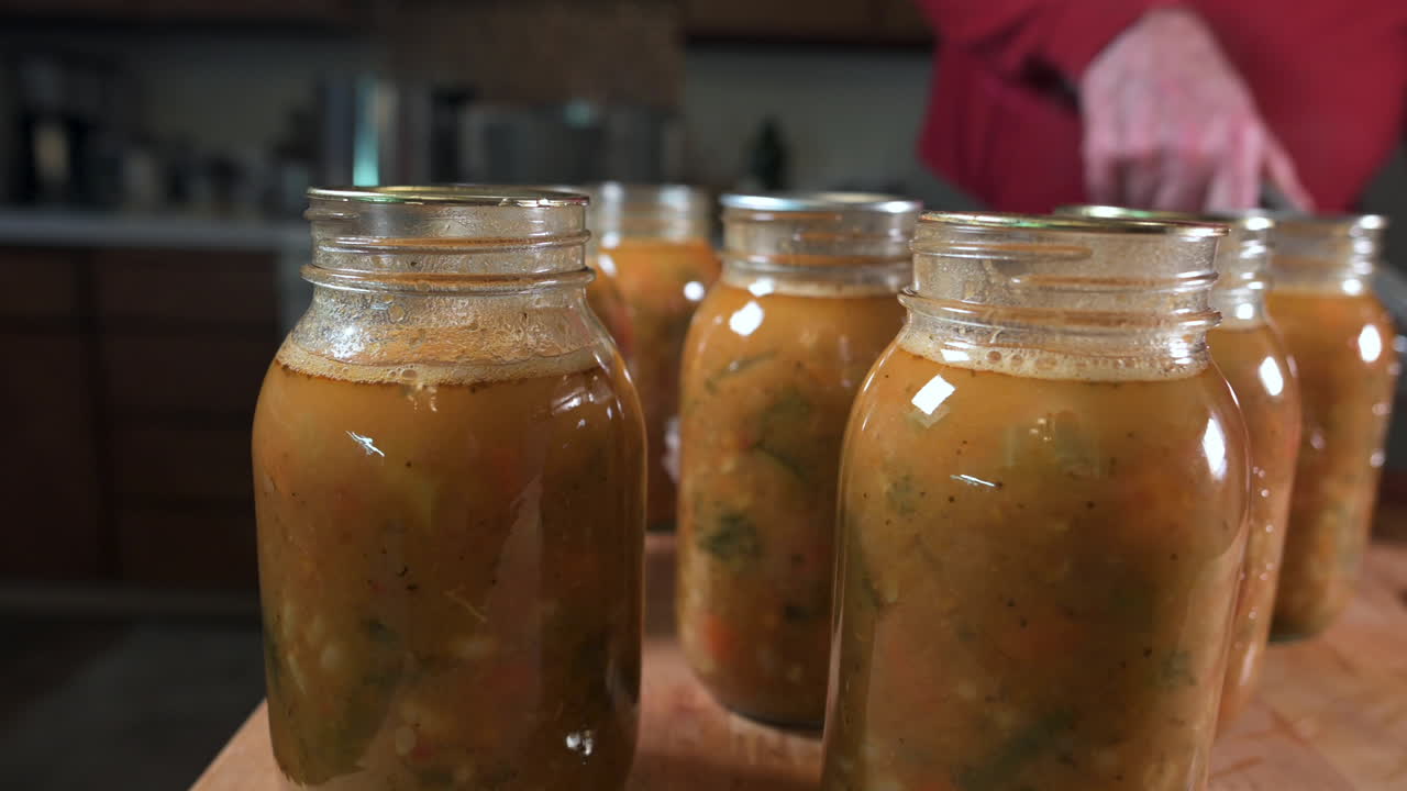 가정 통조림 - 남자는 미네스트로네 수프와 함께 메이슨 항아리에 살균된 통조림 뚜껑을 놓는다 - 클로즈업