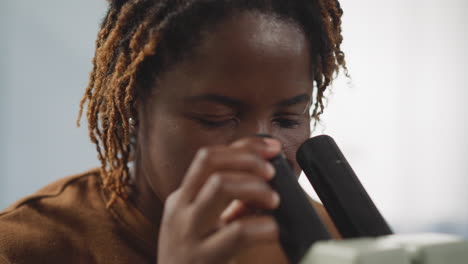 African-American-woman-looks-at-viruses-through-microscope