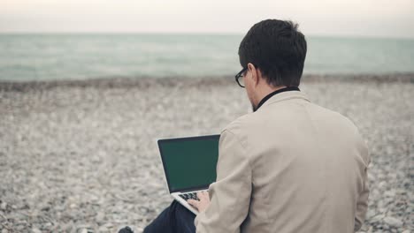 hombre trabajando en una computadora portátil en la playa