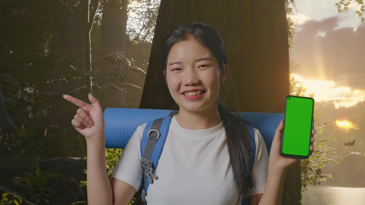 녹색 화면 전화로 숲에서 하이킹하는 젊은 여성