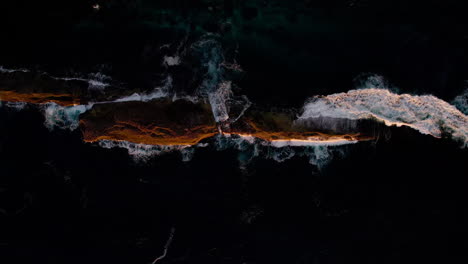 morning sun lights a rock surrounded by shallow sea near warden head lighthouse, ulladulla nsw. gentle waves lap the shore in this peaceful coastal drone shot showcasing nature’s calm beauty.