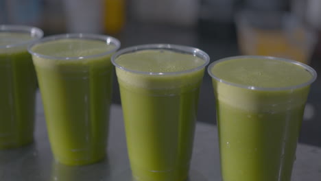 close up dolly of of a row of green juices on a counter