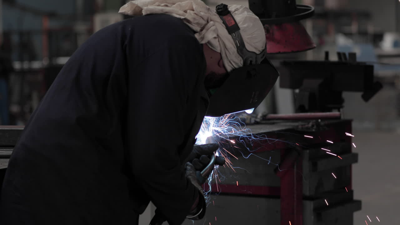 Welder At Work In A Steel Factory - Welding Metal With Sparks Flying - medium shot