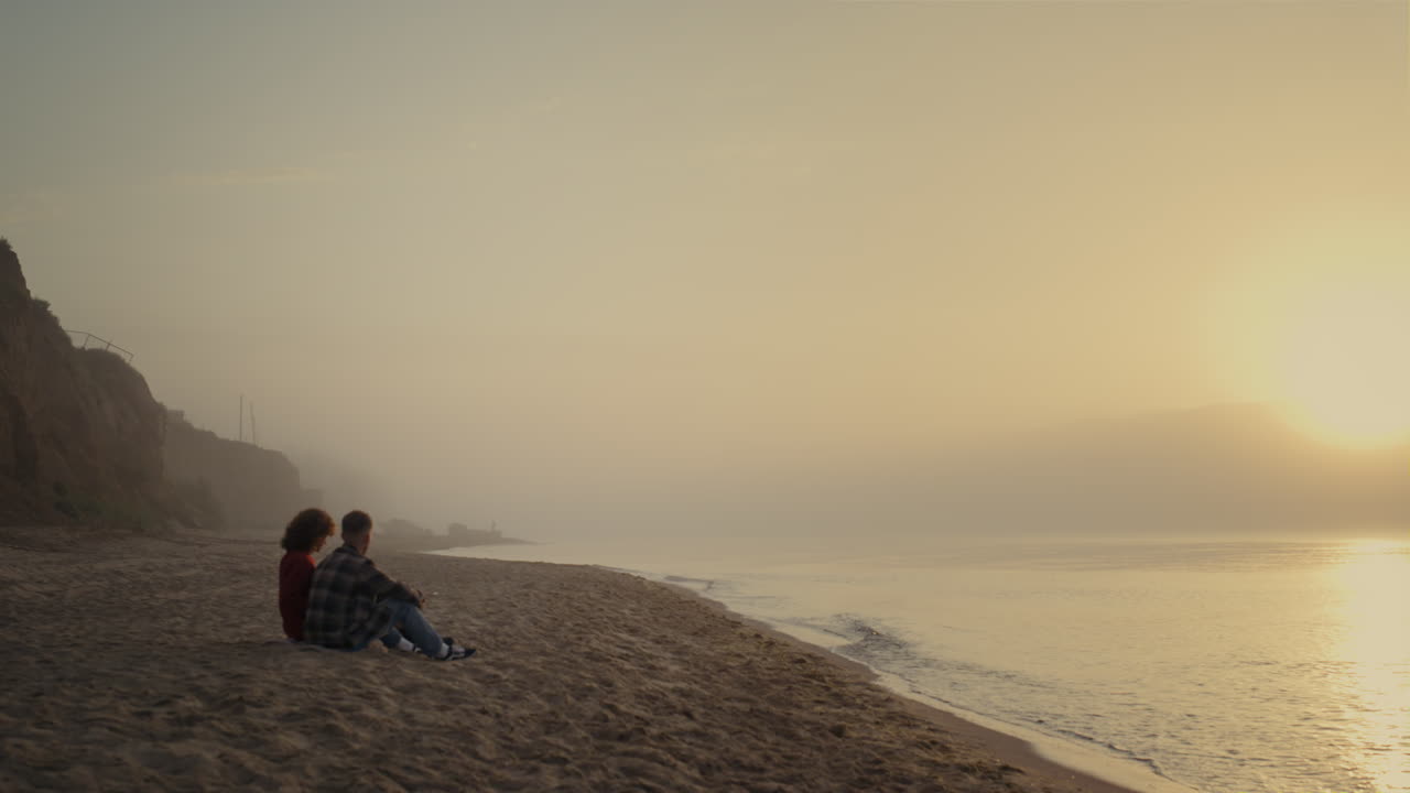 Young woman and man spending vacation at ocean. Couple having date on beach