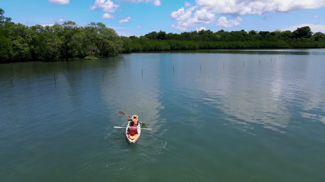 una pareja en un kayak en el océano de phuket, tailandia, hombres y mujeres en un kayak en una isla tropical con palmeras y bosque de manglares.