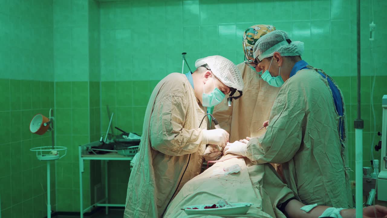 Professional doctors wearing protective clothing performing surgery using sterilized equipment. Medical team performs surgical operation in a big operating room in hospital.