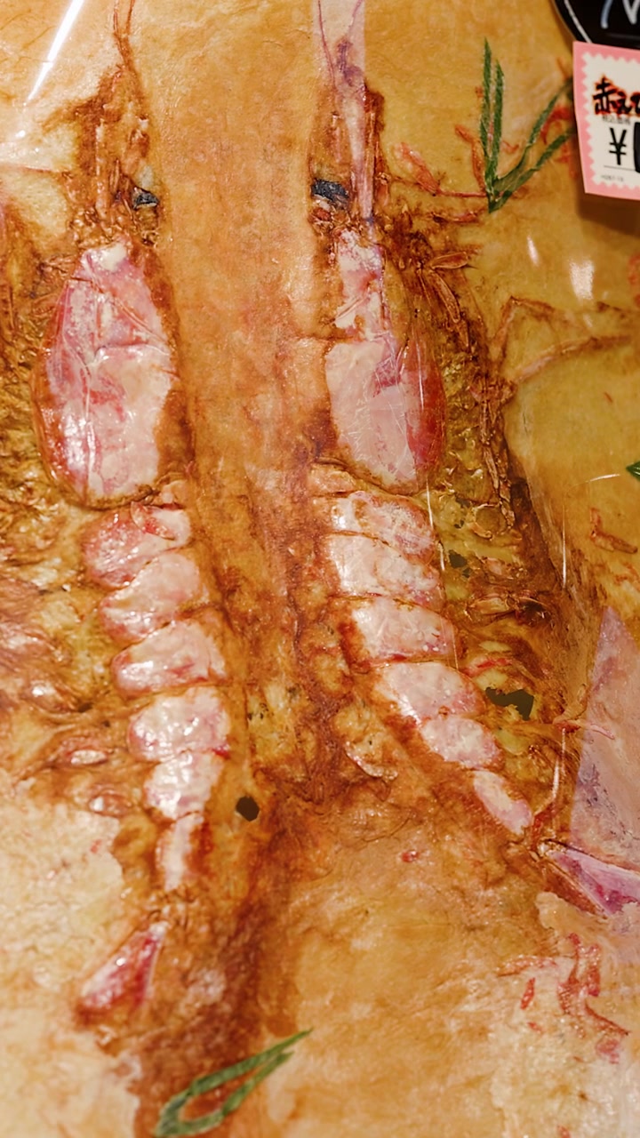 Primo piano di un grande cracker senbei di pesce croccante con gamberi interi pressati a Tokyo