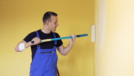 experienced construction worker with paint roller. young man painting wall with roller brush while renovating apartment