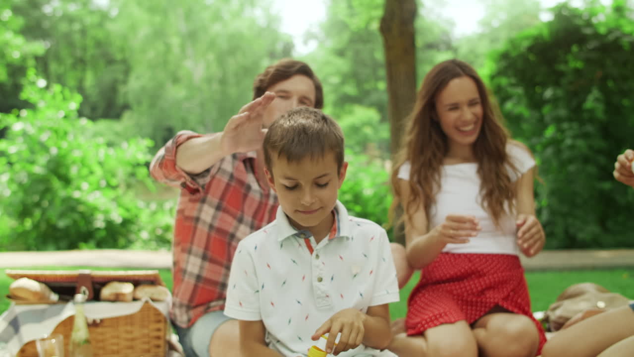 공원에서 비누 거품으로 노는 소녀와 소년. 숲에서 피크닉을 하는 가족