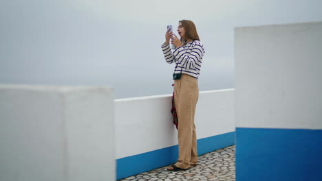 tourist take beautiful pictures of sea town architecture on summer trip vertical