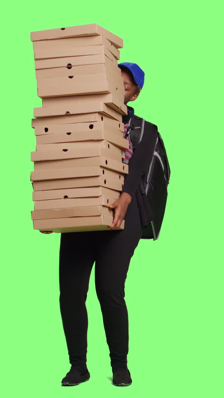 Kurir layanan pengiriman membawa tumpukan besar kotak pizza
