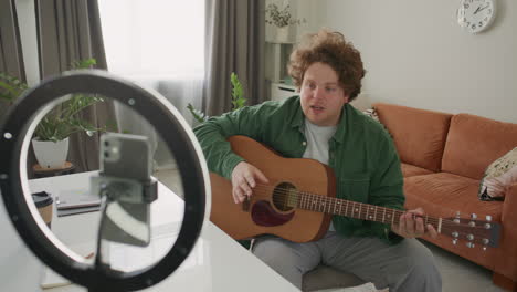 man teaching acoustic guitar chords during online music class