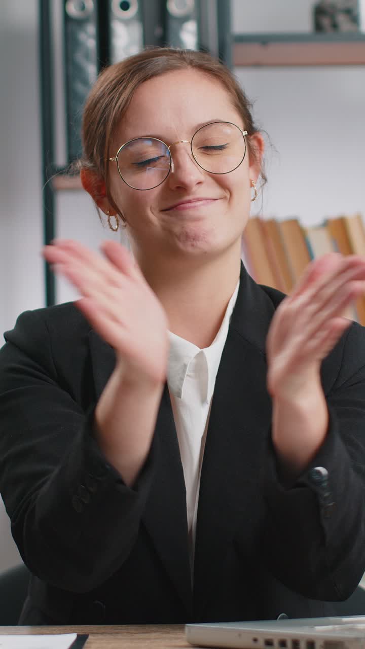 Una donna d'affari felice che guarda con approvazione la telecamera mostrando i pollici in alto come un segno positivo di buone notizie
