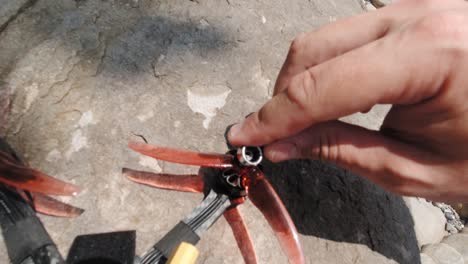 a man's hand tightening the loose screws of drone propellers using a small wrench - closeup shot