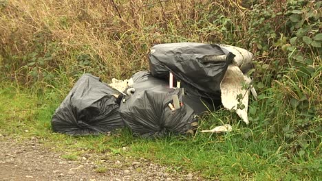 Rubbish-wrapped-in-black-plastic-bags-flytipped-and-dumped-in-a-field-gateway-in-the-beautiful-English-county-of-Rutland-by-criminals