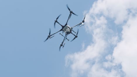 drone sprayer flies over the agricultural field. agriculture drone for spraying fertilizer on the blue sky. smart farming and precision agriculture