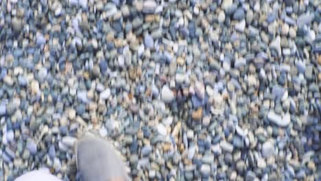 person walking on a pebbly beach