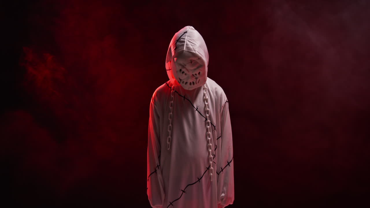 ребёнок в костюме призрака зомби монстра трюк или угощение на хэллоуин пугает людей на фоне красного дыма 10