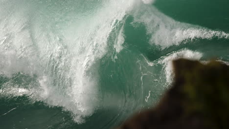 heavy wave barreling in slow motion close to the rocks