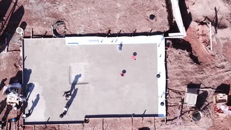 drone descents onto a basement cement building structure in central europe with workers being productive