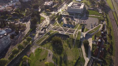 toma aérea de arriba hacia abajo del área del parque rural, conducción de automóviles y edificio del centro de exposiciones de buenos aires al atardecer
