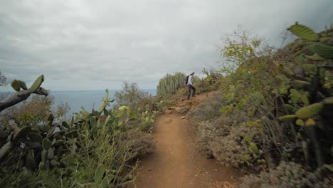 Following-a-female-hiker-in-Anaga-mountains-on-Tenerife,-Spain-with-a-view-over-mountains-and-the-ocean