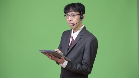 joven empresario asiático usando una tableta digital mientras trabajaba como representante de un centro de llamadas