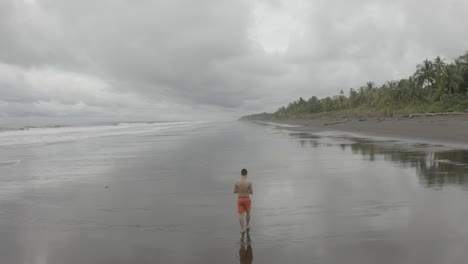 Antenne-Fliegt-über-Einen-Jungen-Mann,-Der-An-Einem-Leeren-Strand-In-Kolumbien-Spazieren-Geht