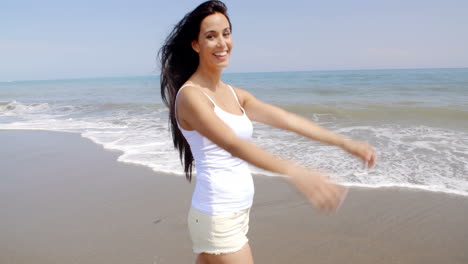 Carefree-Woman-Standing-on-Beach-with-Arms-in-Air