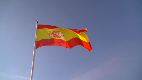 incredible view of spanish flag waving in wind against blue sky