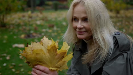 portrait of beautiful blonde woman sitting in foliage. smiling elderly lady .