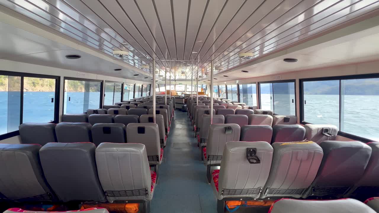 Empty boat interior with seats, windows showcasing ocean view, Patagonia journey vibe
