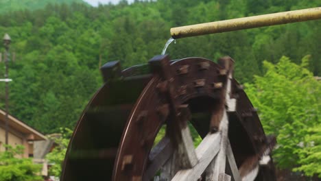 Water-Coming-Out-Of-Pipe-Onto-Spinning-Traditional-Water-Wheel-In-Village-Town-Of-Shirakawago