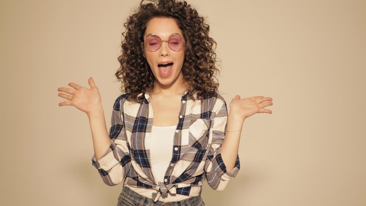Mujer feliz con cabello rizado y gafas de sol rosas
