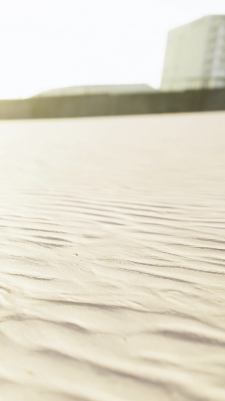 Ripples in the sand at a beach during sunset near a city