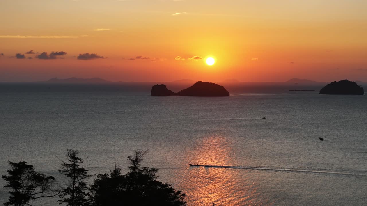 vista de pájaro desde detrás de una copa de árbol mirando hacia el mar abierto con islas en la distancia y el barco viajando por el canal