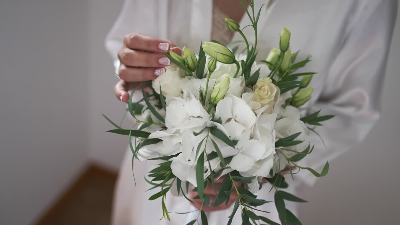 Sposa che tiene un delicato bouquet floreale bianco.