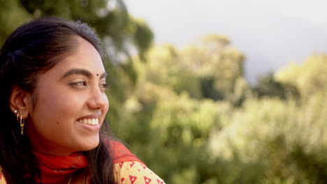 smiling indian woman in traditional sari enjoying nature outdoors, looking content, copy space